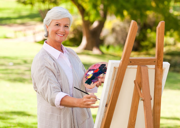 Mature lady painting outdoors Woman painting at an easel outside