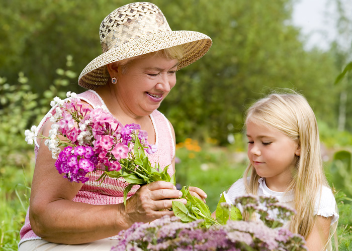 Lady in straw hat with granddaughter Grandmother and child picking flowers outside.