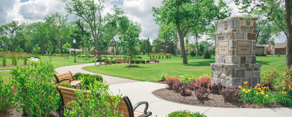 Large stone marker surrounded by landscaping and benches